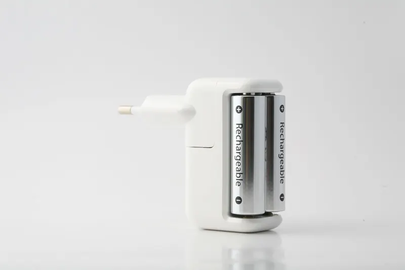 Minimalist shot of a rechargeable battery charger with two batteries on a white backdrop