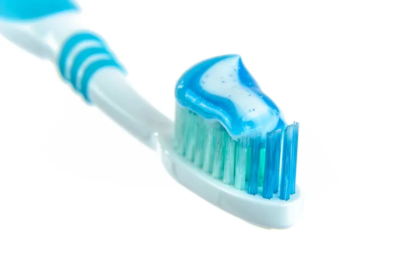 Detailed close-up image of a toothbrush with vibrant blue toothpaste for dental hygiene