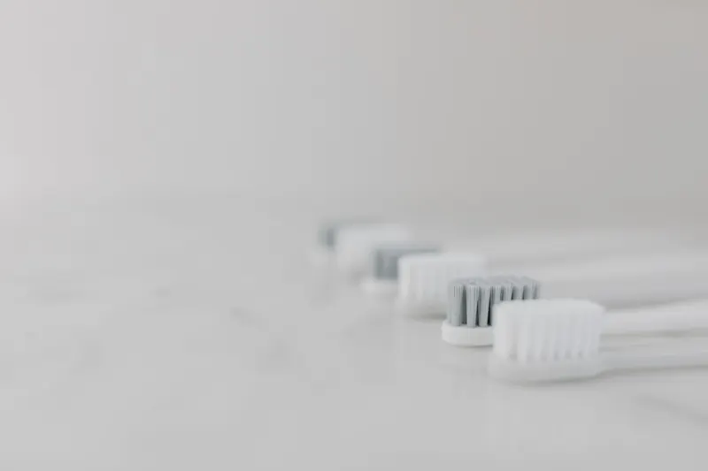 A modern and clean still life composition featuring multiple toothbrushes aligned on a marble surface with copy space