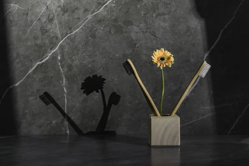A modern toothbrush holder with a sunflower on a gray surface