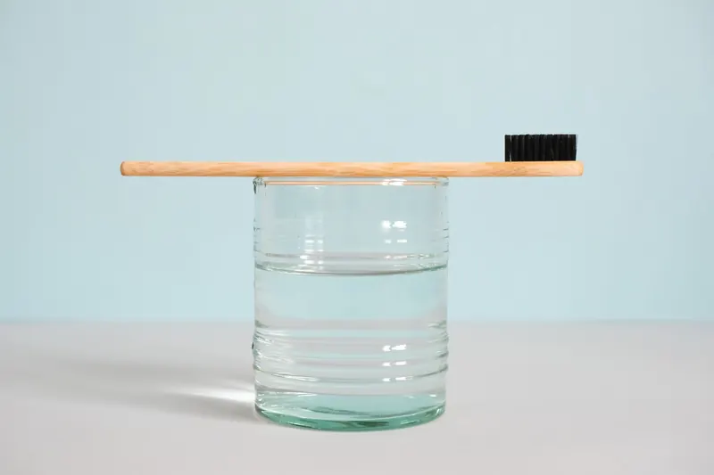 Minimalist image of a bamboo toothbrush atop a glass of water, emphasizing sustainable hygiene