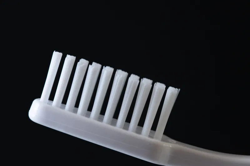 Detailed close-up of a white toothbrush on a black background, ideal for dental hygiene concepts