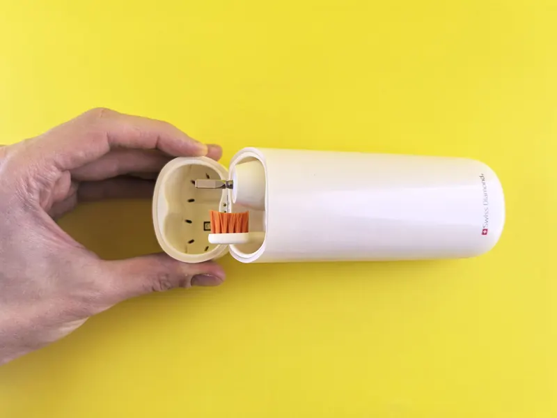 A stylish portable electric toothbrush with a sleek protective case against a vibrant yellow backdrop