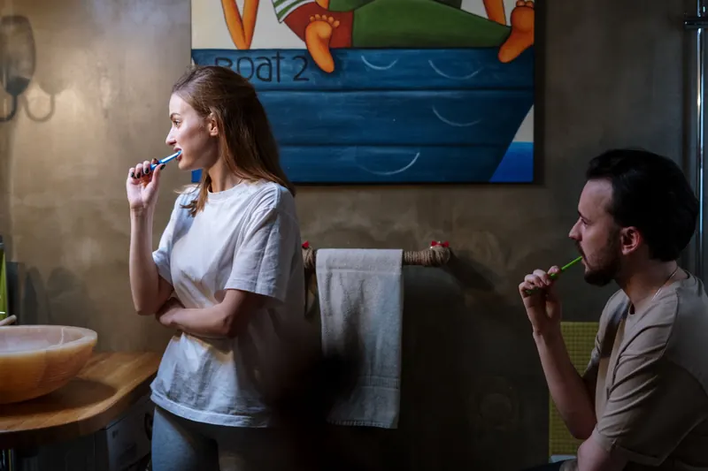 A couple brushing their teeth in a cozy bathroom during their morning routine